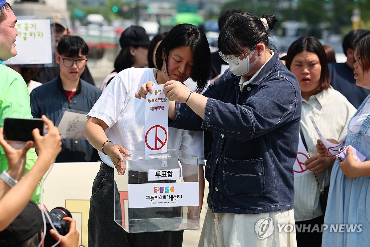 제21대 대통령 선거 사전투표 첫날인 29일 서울 종로구 광화문광장에서 열린 발달장애인 참정권 보장 요구 기자회견에서 참가자들이 투표함에 요구사항이 적힌 투표지를 넣는 퍼포먼스를 하고 있다. 이들은 발달장애인의 참정권 보장을 위해 투표보조 보장, 이해하기 쉬운 자료 제작, 그림투표보조용구 지원, 모의투표 실시 등을 촉구했다.